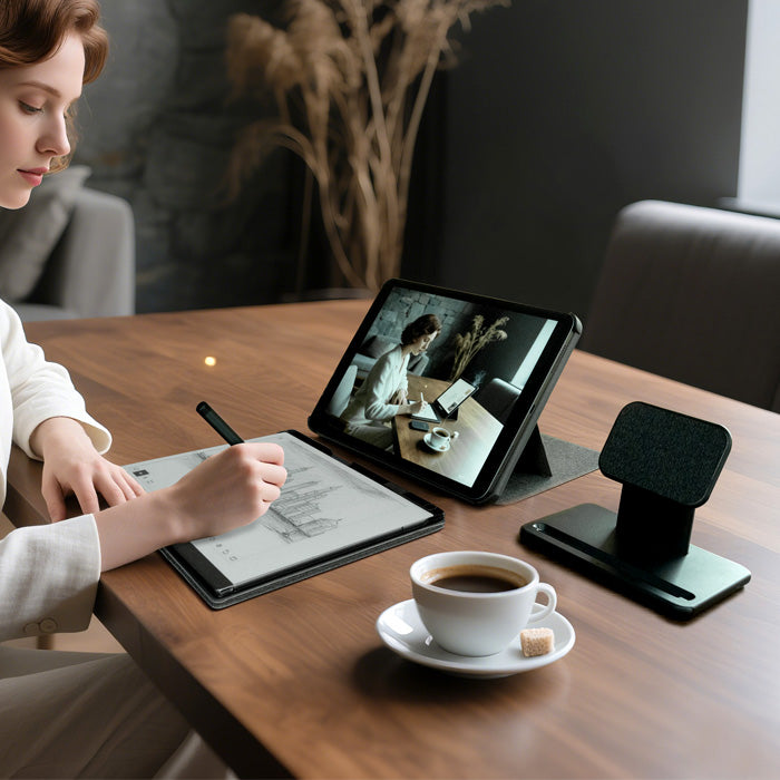 woman using a stylus on a digital drawing tablet with a cup of coffee on a wooden table.